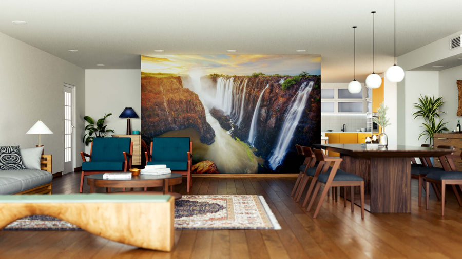 Modern open-plan living and dining area with wooden floors, stylish furniture, and the Victoria Falls in Zambia Wall Mural as a vibrant focal point. Warm lighting and plants add coziness to this contemporary space.