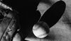 The Vintage Baseball Wall Mural features a black and white image of a worn glove and baseball on textured ground. Dramatic shadows add contrast, making this peel and stick mural ideal for any baseball fan’s space.