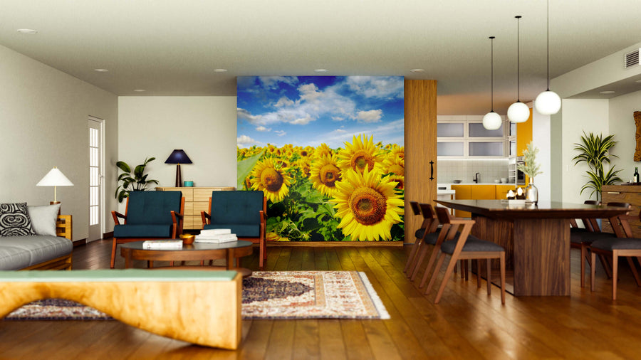 A modern open-plan living and dining area features wooden floors, stylish furniture, and the Vivid Sunflower Field Wall Mural, bringing a vibrant sunflower field under a blue sky to life. Contemporary lighting enhances the bright, inviting ambiance.