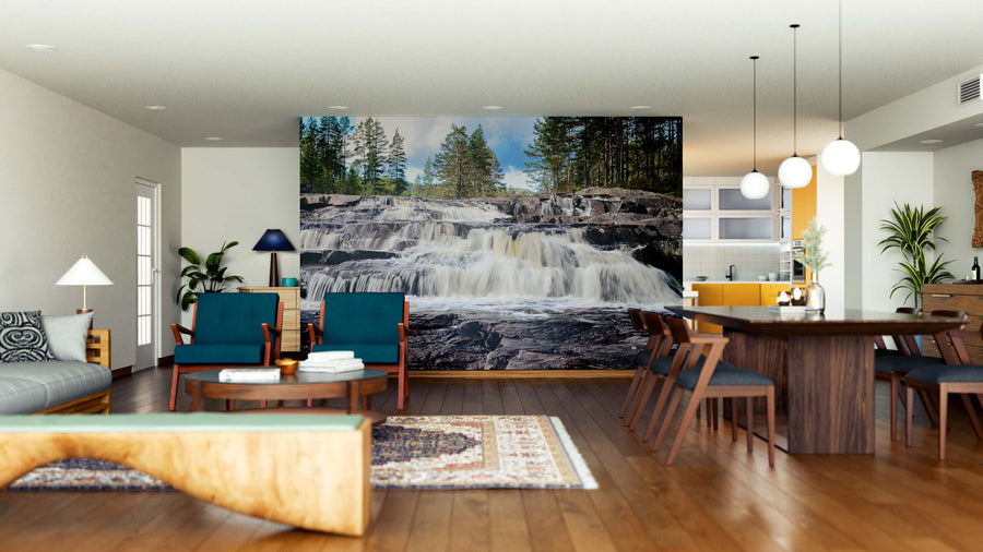 A modern open living and dining area with wooden floors, blue and wooden furniture, and pendant lights features the Waterfall in Forest Wall Mural, creating a natural, serene focal point with its imagery of cascading water and trees.