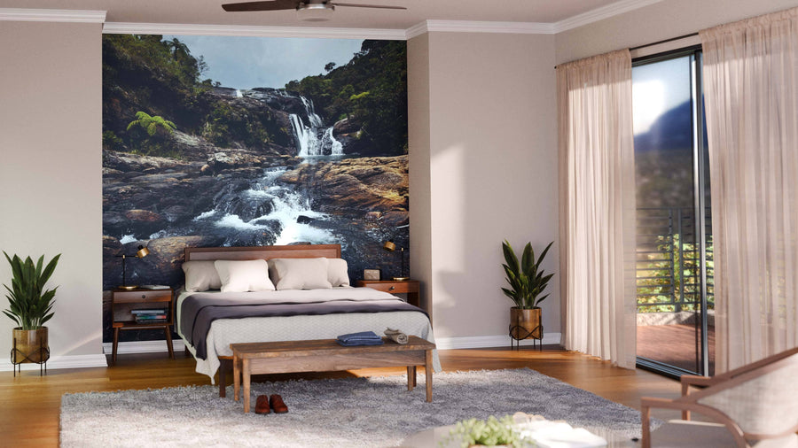 A modern open-plan living and dining room with wooden floors, teal armchairs, a large “Waterfalls in Sri Lanka” Wall Mural, a six-seat dining table, pendant lights, and a yellow-accented kitchen in the background.