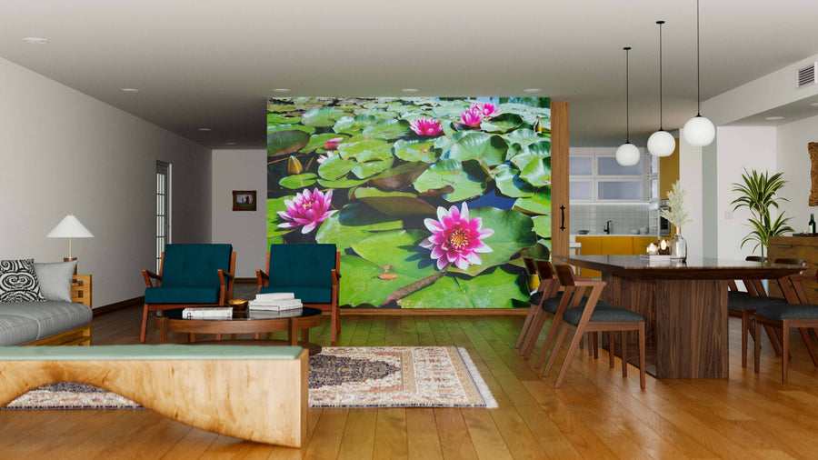 A modern open-plan living and dining area with wooden floors and furniture features the Waterlilies Wall Mural of pink water lilies and green lily pads, creating a focal point that separates the blue chairs in the living area from the dining space.