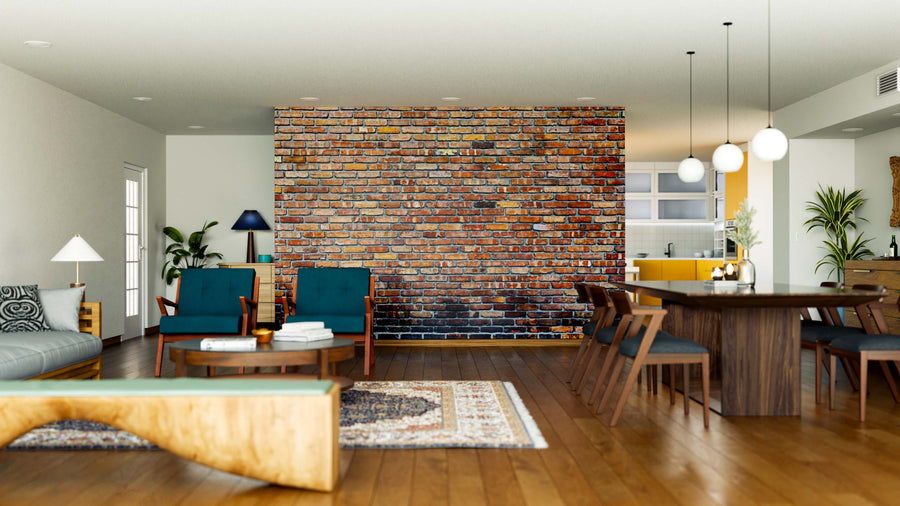 A modern open-plan living and dining area features a Weathered Brick Wall Mural, wooden floors, green armchairs, a gray sofa, ceiling lights, houseplants, and a rug, with the kitchen visible in the background.