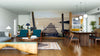 A modern open-concept living and dining area features wooden floors, teal chairs, a wooden dining table, and the Weathered Dock at Sunset Wall Mural as a serene focal point.