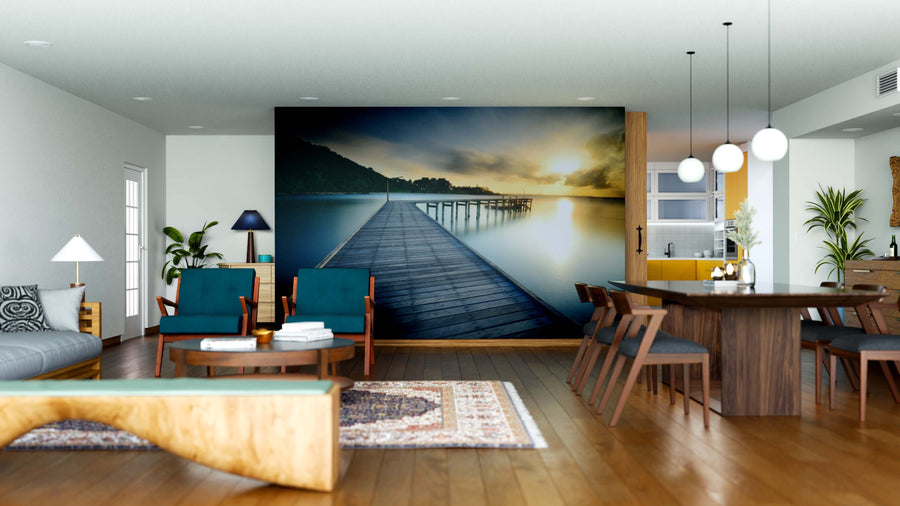 A modern living-dining room with wooden floors, teal chairs, a sofa, and a long table. The Wooden Bridge with Sunrise Wall Mural adds depth, while plants, pendant lights, and décor create a cozy, welcoming vibe.