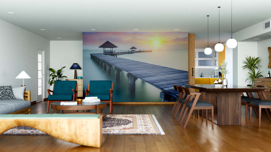 Modern open living-dining area with wooden floors, blue chairs, a Wooden Dock at Sunset Wall Mural, dark dining table, contemporary pendant lights, and warm decor that enhance the room’s stylish feel.