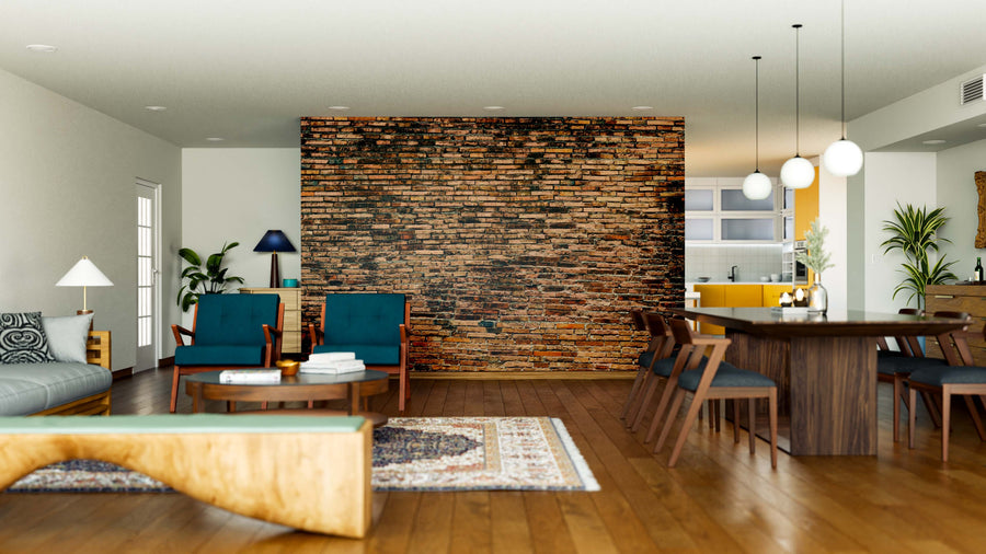A modern open-plan living and dining room with wooden floors, teal armchairs, a gray sofa, a wooden bench, pendant lights, yellow kitchen cabinets in the background, and a Worn Brick Wall Mural as an accent wall.