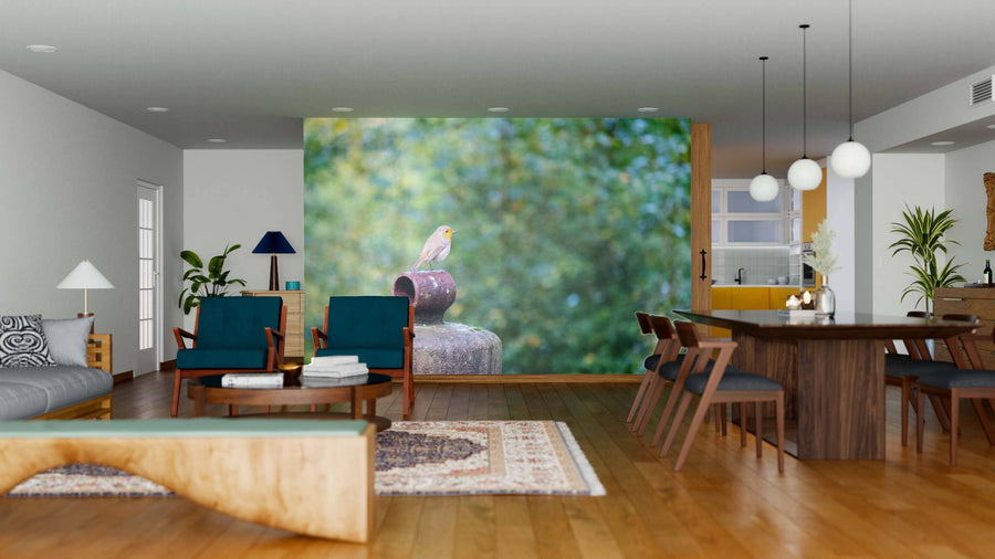 A modern open-plan living and dining area with wood floors, blue chairs, and a wooden table features the European Robin Erithacus Wall Mural—showing a bird on a rustic pipe set against a lush green, blurred backdrop.