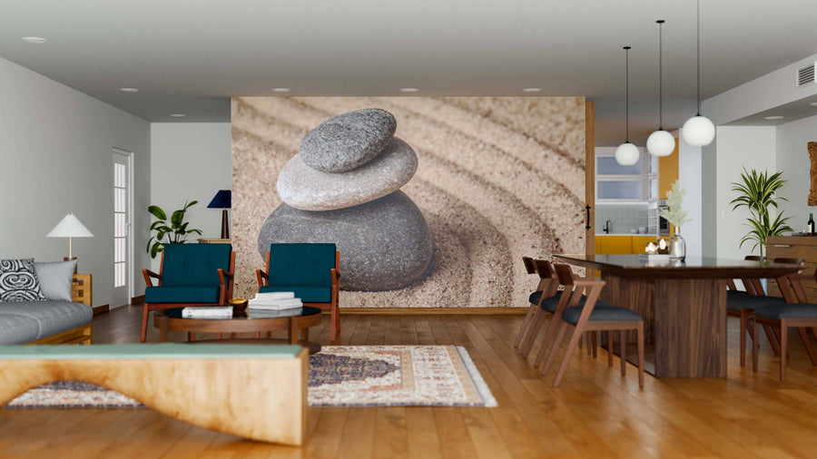 A modern open living-dining room with wood floors, teal chairs, and a large Japanese Zen Stone Garden Wall Mural depicting three stacked stones on sand. Pendant lights hang above the table, with the kitchen visible in the background.