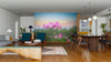 A modern open-plan living and dining room features wooden floors, teal chairs, a wooden dining table, and the Lotus Flower in Sunset Wall Mural. Warm decor and pendant lights complete this inviting space.