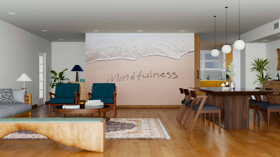 A modern open-plan living and dining area features wood floors, teal chairs, plants, pendant lights, a rug, and a kitchen. The space is highlighted by the Mindfulness Wall Mural with sand and ocean waves and “Mindfulness” in the sand.