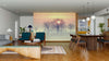 A modern open-plan living and dining room with wooden floors, teal chairs, and a rug. The back wall features the Sunrise Through Trees Wall Mural, adding a serene touch of misty sunrise and bare trees under contemporary lighting.