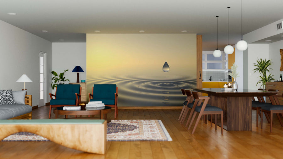 A modern open-plan living and dining area features wood floors, teal chairs, and a Zen Drop Wall Mural showing a water droplet with ripples on a yellow gradient. Pendant lights hang above the dark table, while rugs and houseplants add warmth.