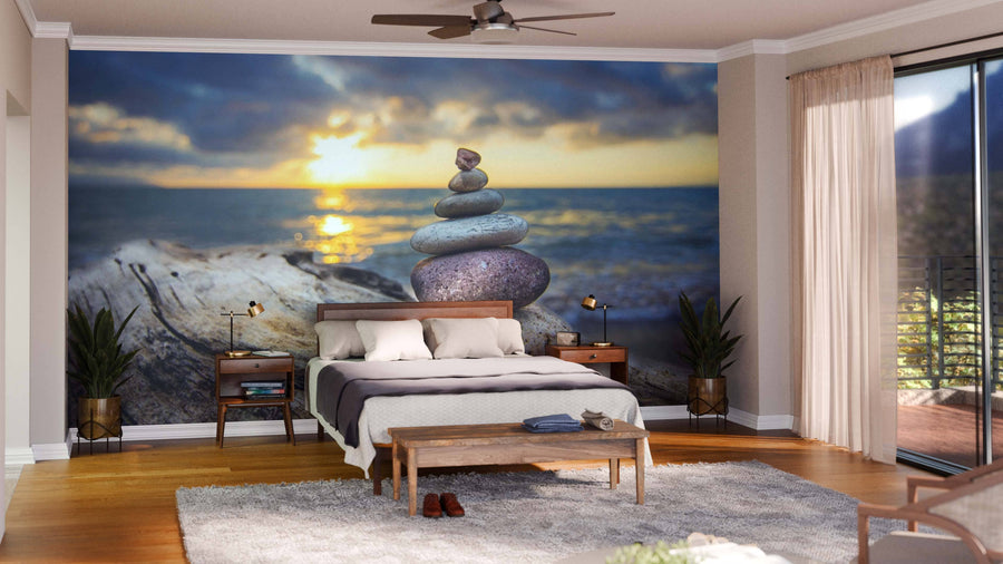 A modern bedroom with a bed, wooden bench, and plants features the Zen Stones on the Beach Wall Mural. Large windows with sheer curtains fill the space with natural light, while a ceiling fan hangs above.