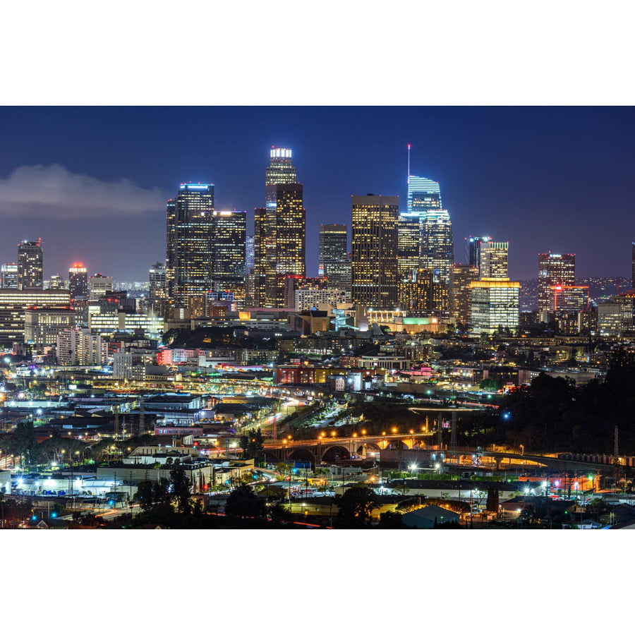 A modern conference room features a long wooden table, black chairs, floor-to-ceiling windows, and a Downtown LA Wall Mural on the far wall showcasing a city skyline at night with illuminated skyscrapers and bright lights.