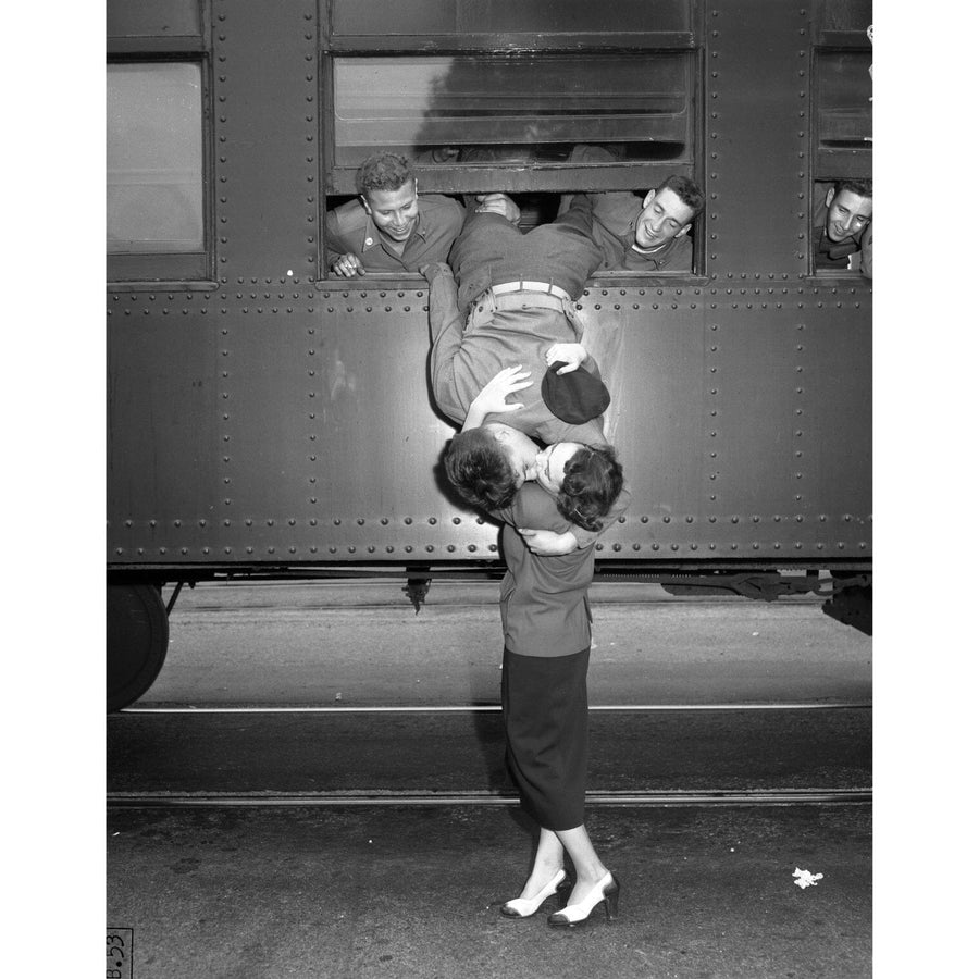 A woman in high heels kisses a man in uniform leaning out of a train window upside down as three others watch with smiles. The Sweet Goodbyes Wall Mural by PLANES, TRAINS & AUTOMOBILES captures this farewell, evoking nostalgia like a peel and stick mural turning moments into memories.
